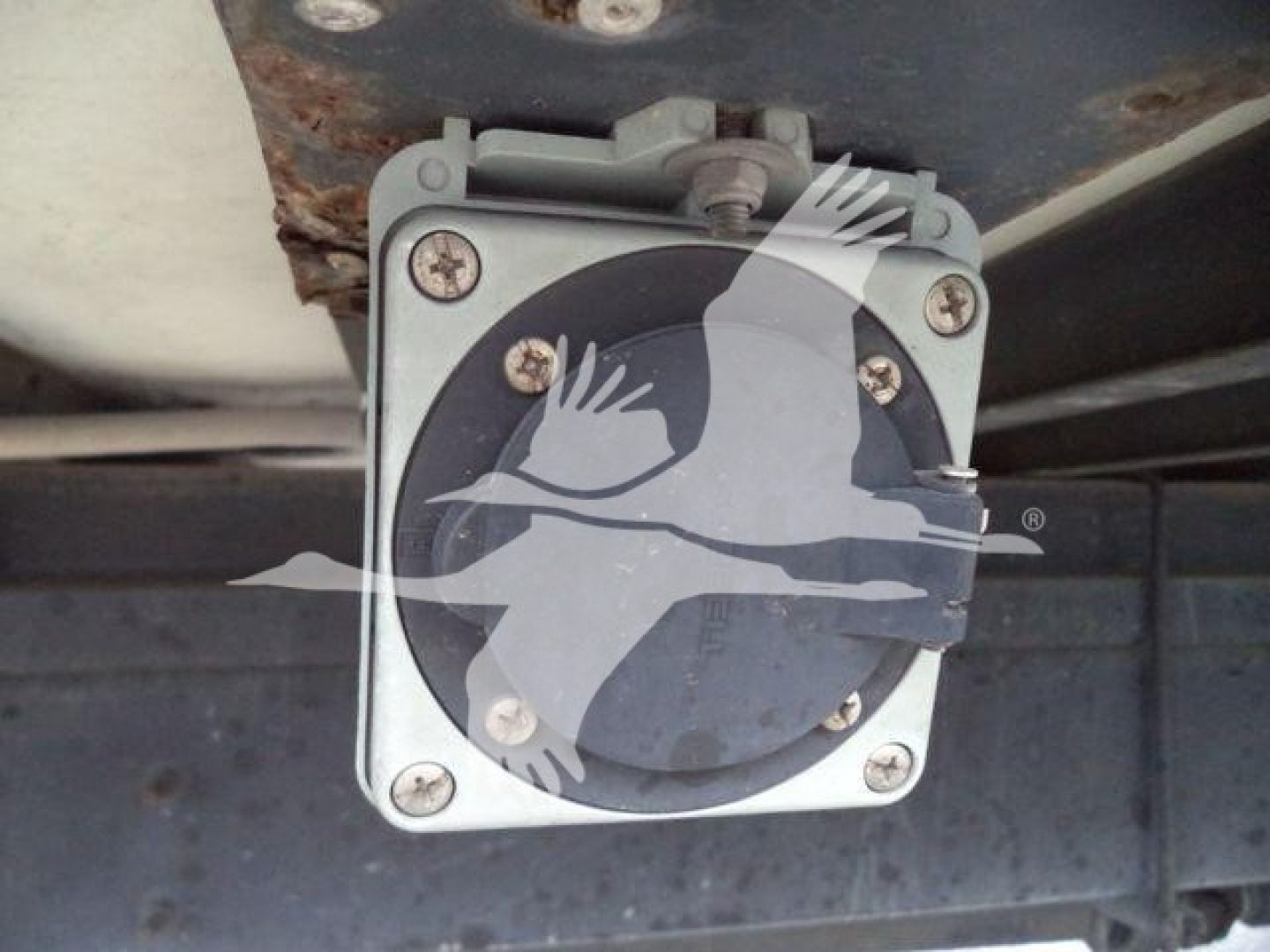 Hino 268A undercarriage showing a square electrical component with a circular black dial and four screws at corners.