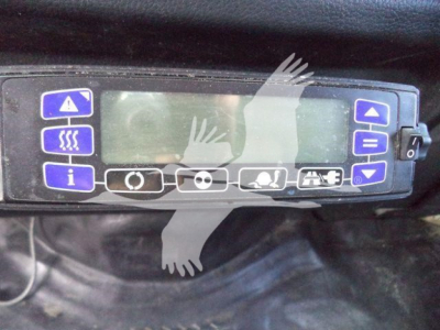Dashboard control panel with blue buttons and display screen in a refrigerated truck cab.