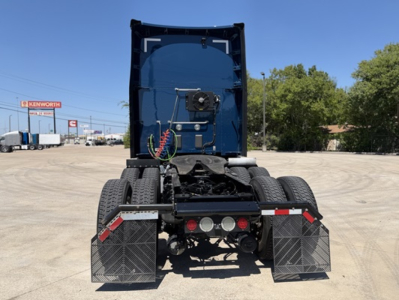 Kenworth T680 rear view showing dual rear axles, chassis, and mud flaps with warning reflectors.