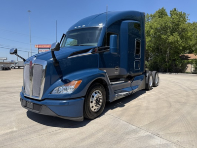 Kenworth T680 tractor showing front grille, headlights, blue exterior, sleeper cab, and tandem rear axles.