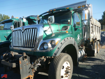 International WorkStar 7600 dump truck with plow and wing, green cab, chrome grille, large front bumper, heavy-duty front tires, bed in rear.