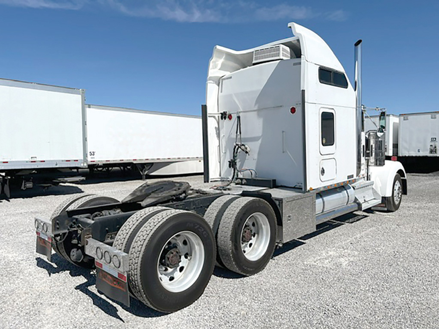 Kenworth W-900L truck tractor rear view showing sleeper cab, dual rear axles, and fifth wheel with fuel tanks.