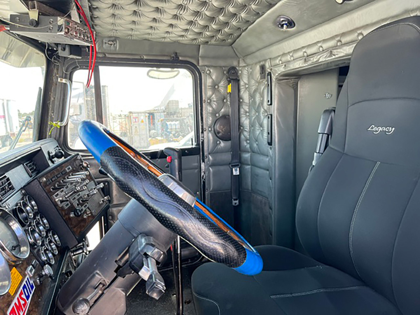 Kenworth W-900L interior showing steering wheel, dashboard, and driver seat with leather cover.