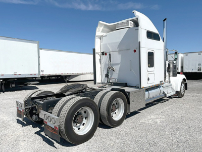 Kenworth W-900L truck tractor rear view showing sleeper cab, dual rear axles, and fifth wheel with fuel tanks.