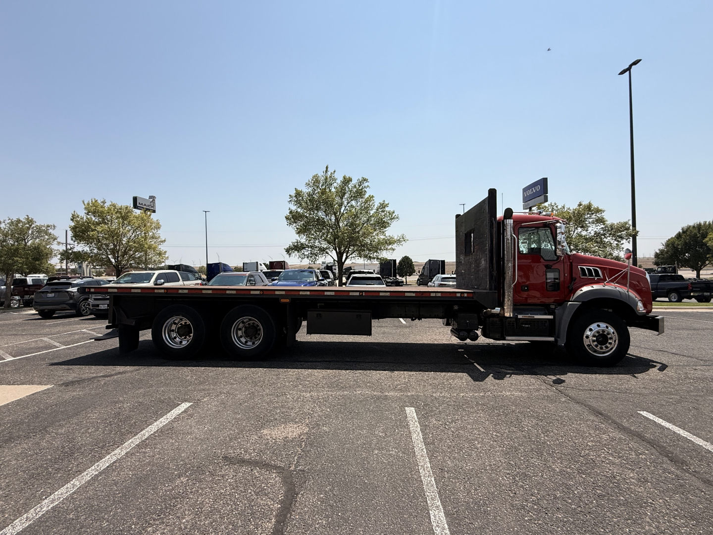 Side view of a red 2020 Mack Granite flatbed truck in a dealership lot with stock number B3720P and VIN 1M2GR2GC4LM017067.