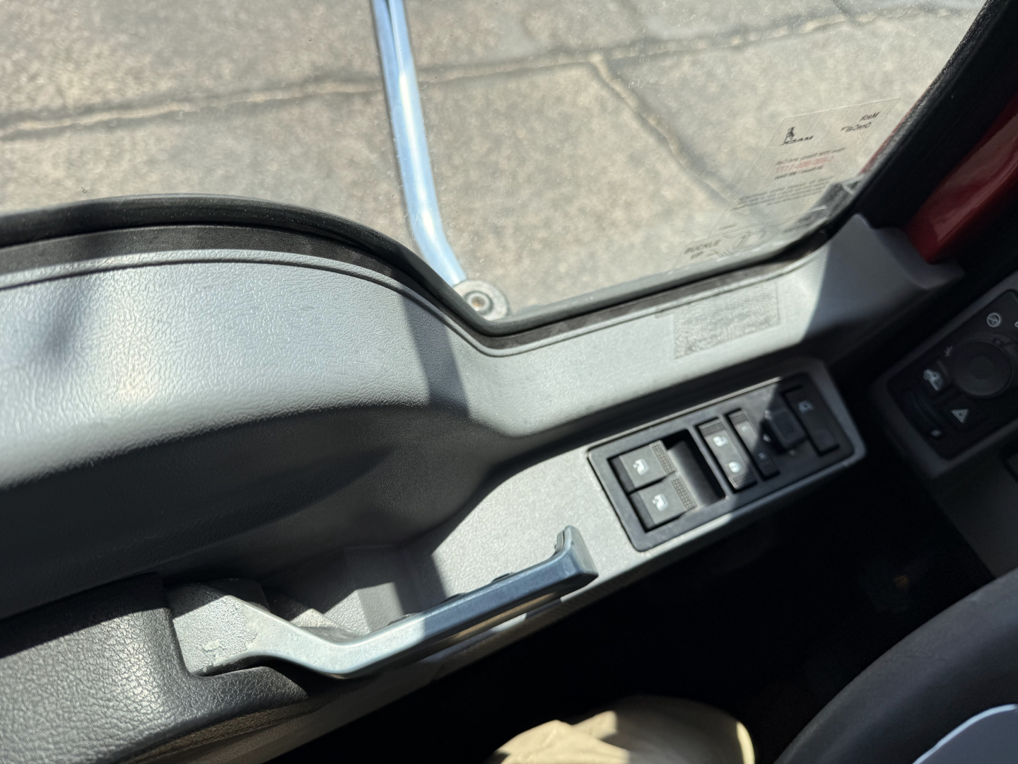 Mack GRANITE truck cab interior window area showing control switches on the door panel and armrest; no engine or exterior details visible.