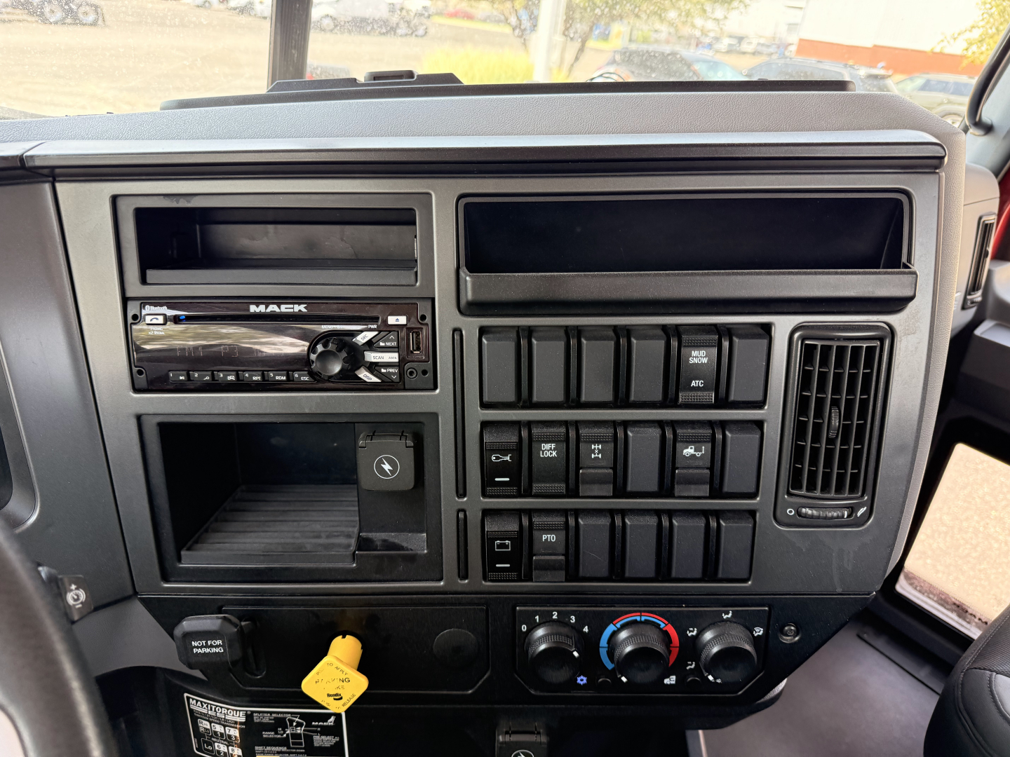 Truck interior dashboard showing radio, switch panel, climate controls, and dashboard compartments in a Mack Granite cab.