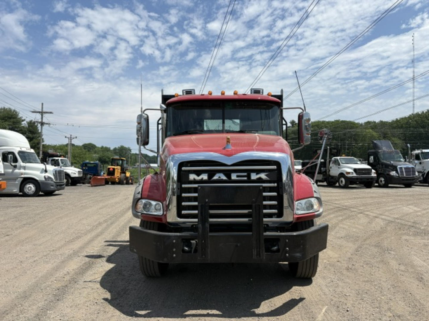 Front view of a red 2020 Mack GRANITE heavy-duty truck with large chrome grille, bumper guard, and side mirrors in a dealership lot.