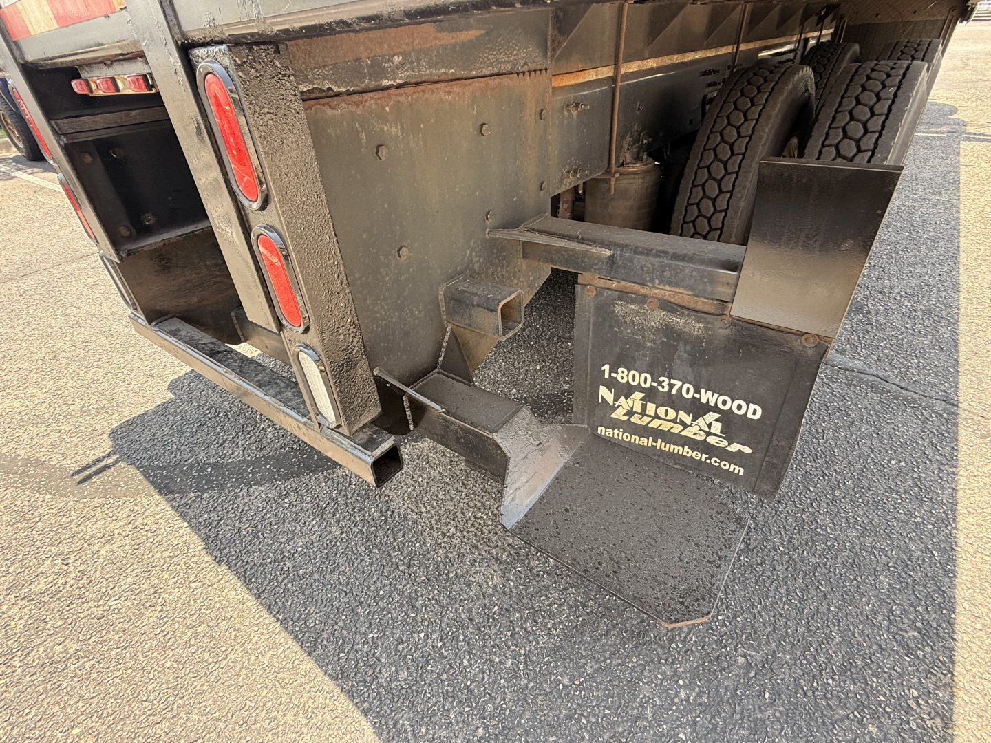 Rear view of a 2020 Mack Granite flatbed truck showing bumper, mudflaps with National Lumber logo, and tail area.