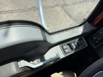 Mack GRANITE truck cab interior window area showing control switches on the door panel and armrest; no engine or exterior details visible.