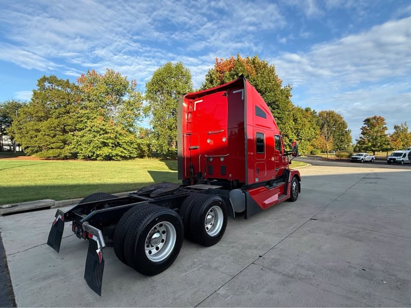 Kenworth T680 tractor chassis and red sleeper cab, rear three-quarter view, with dual rear axles and fifth wheel, outdoor lot