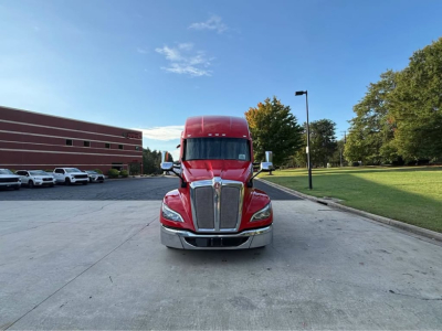 Kenworth T680 truck front view in red cab with chrome grille and headlights, parked in lot.