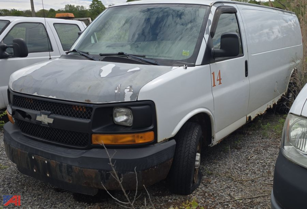 Chevrolet Express 2007 cargo van with faded white paint, black front bumper, orange turn signal, orange '14' on side, parked in a lot.