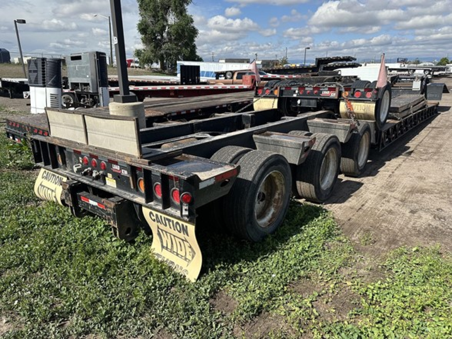 Load King lowboy trailer with multiple axles and yellow caution mudflaps, rear view showing tires and deck, VIN 150120525536 plate area, stock 28430.