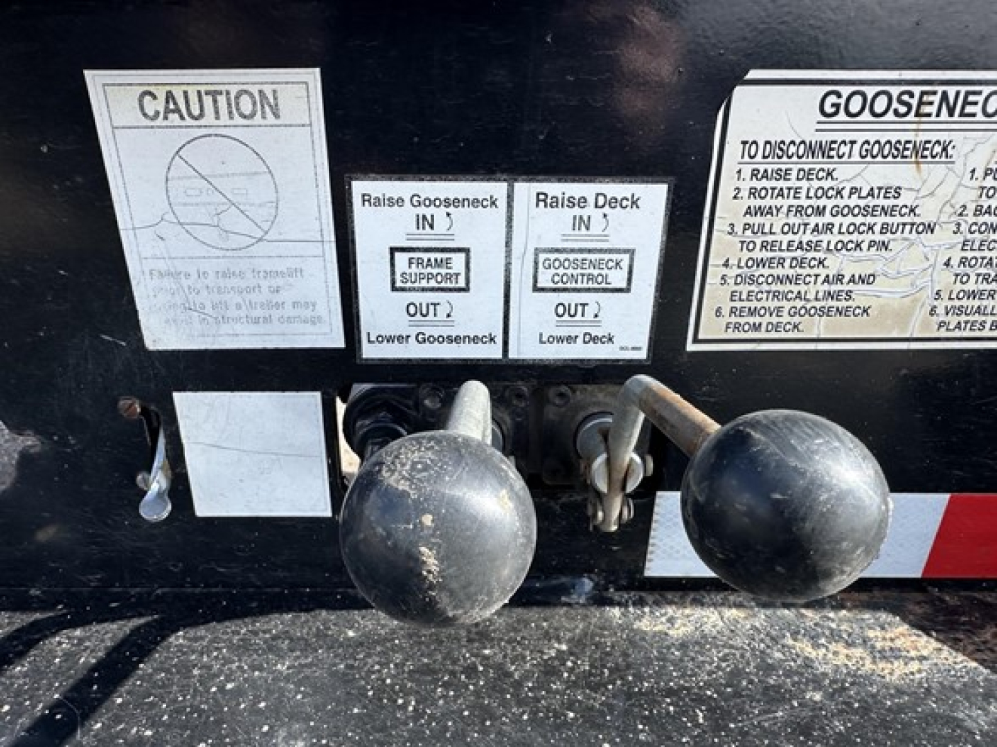 Trailer hitch area with warning decals and instructions, showing labels for cage/Gooseneck setup and operation notes.