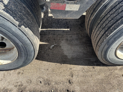 Trailer dual rear tires of a Load King lowboy with West Coast spreader bar, showing tires and dirt on the frame.