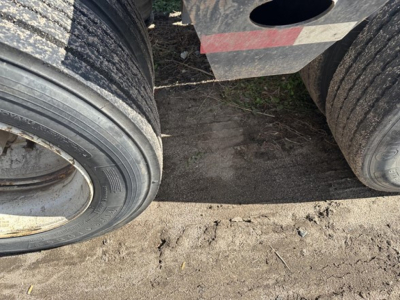 Trailer tires and part of Load King lowboy trailer visible with dirt and mud on tires.