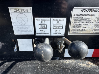 Trailer hitch area with warning decals and instructions, showing labels for cage/Gooseneck setup and operation notes.
