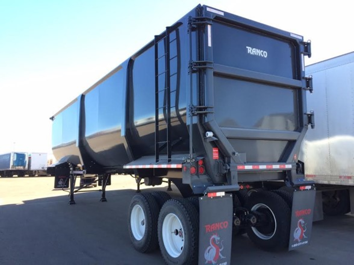 Ranco Ed85-42 dump trailer showing rear and side, black body with white wheels and red-and-white safety decals.