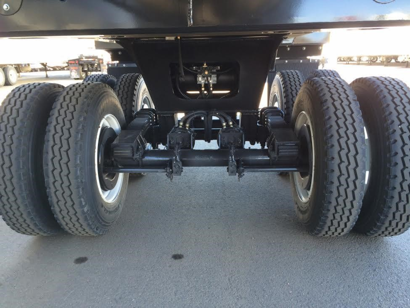 Trailer undercarriage showing twin axles and suspension with dual tires, branding not visible.