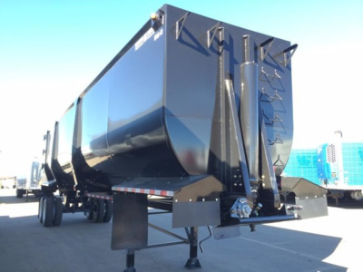 Dump trailer showing ED85-42 chassis and rear end with ladder rungs and support legs, black glossy finish, clear sky.