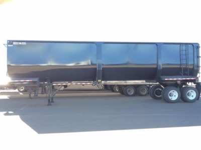 Ranco Ed85-42 dump trailer side view showing black steel bed, tandem axles, and ladder on rear; no visible text legible.