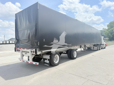 Curtainside trailer by Benson Conestoga with gray tarp, rear doors, and winged graphic; dual rear axles, parked in lot.
