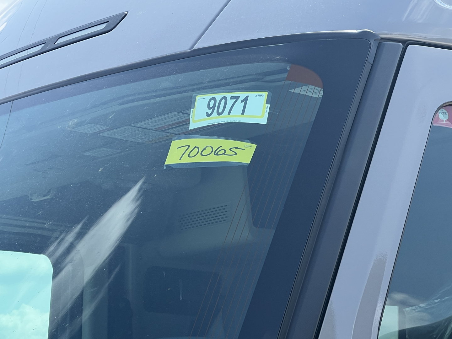 Front windshield of a new Volvo VNL64T860 sleeper cab showing stock tag 70065 and VIN 4V4BC9EHXTN709811 on the dash.