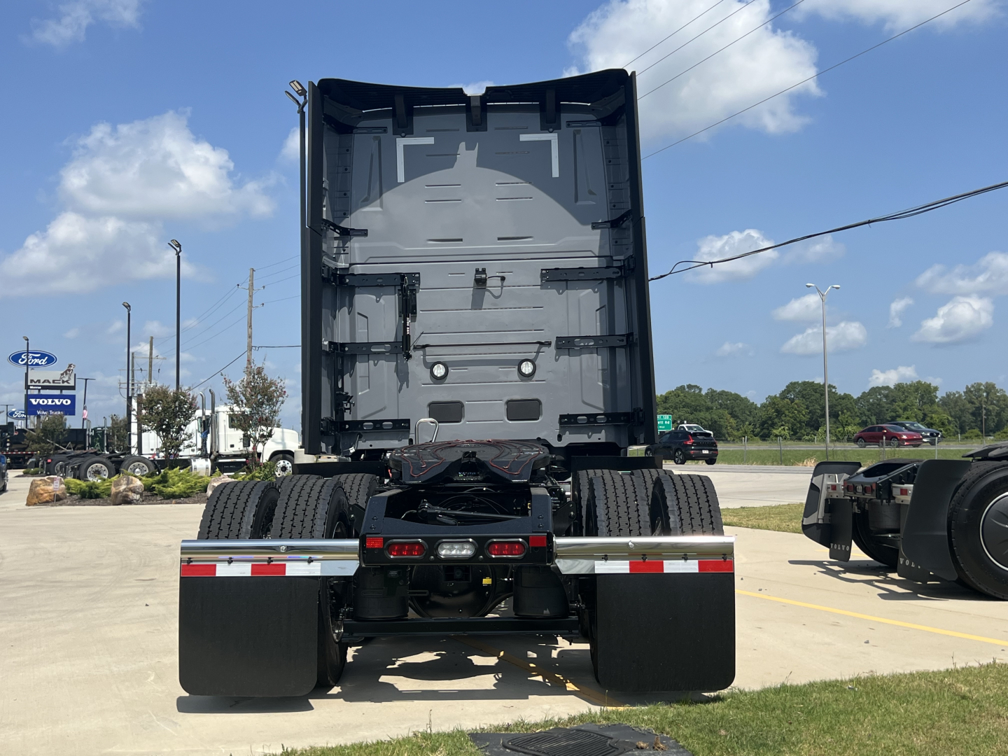Volvo VNL64T860 truck rear view showing chassis and fifth wheel area with dual rear axles and drivetrain, under clear sky
