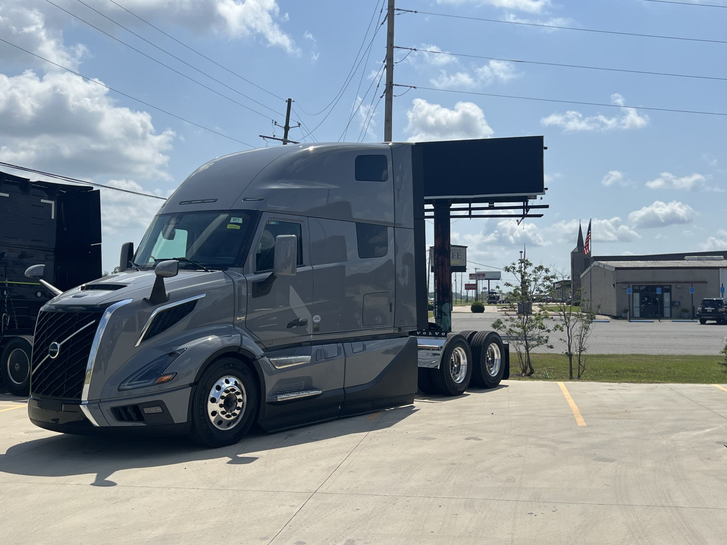 Volvo VNL64T860 conventional sleeper truck in gray, side view showing aerodynamic cab, hood, and tandem rear axles with a dump trailer behind. No visible text readable.
