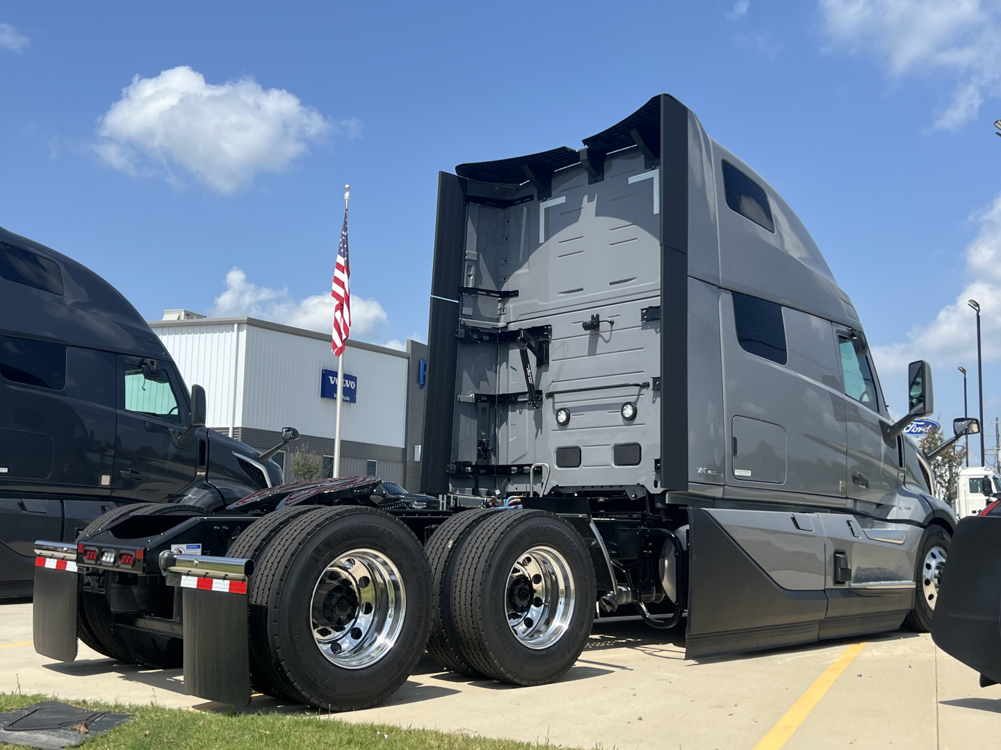 Volvo VNL64T860 truck cab rear view showing dual rear axles and fifth wheel with chrome rims and black body panels.