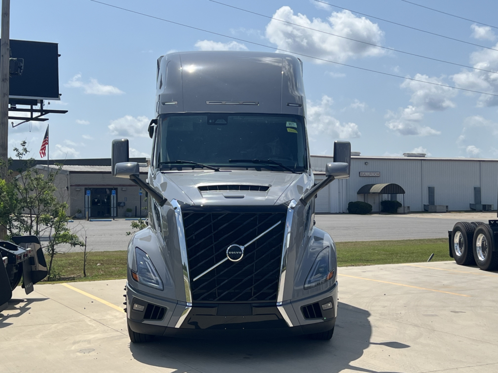 Front view of a new Volvo VNL64T860 conventional sleeper truck showing chrome grille, Volvo emblem, large headlights, and aerodynamic bumper.