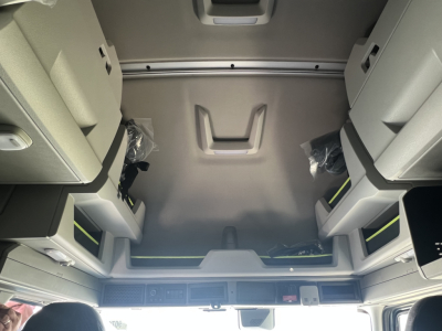 Cab interior of a new Volvo VNL64T860, forward sleeper area showing overhead storage, side panels, and elevated footwell with light gray trim.