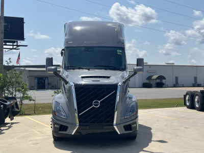 Front view of a new Volvo VNL64T860 conventional sleeper truck showing chrome grille, Volvo emblem, large headlights, and aerodynamic bumper.