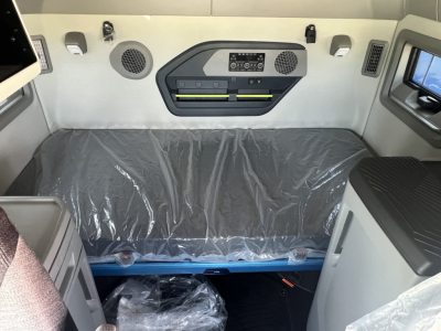 Volvo VNL64T860 sleeper cab interior showing cargo area with protective plastic cover and controls on bulkhead.