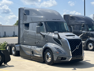 Volvo VNL64T860 truck shown in a lot, front three-quarter view, gray exterior with sleeper cab, large grille, and aerodynamic design.