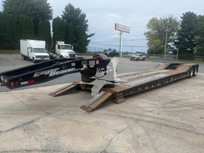Lowboy trailer showing Eager Beaver 35Gsl-PT branding, loading ramps deployed, near a truck lot.