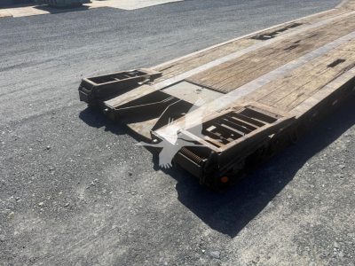 Lowboy trailer bed showing wooden deck and tail section with metal frame and wheel ramps.