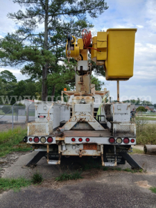 Back view of a 1986 GMC 7000 bucket truck with a large yellow bucket crane and weathered metal chassis.