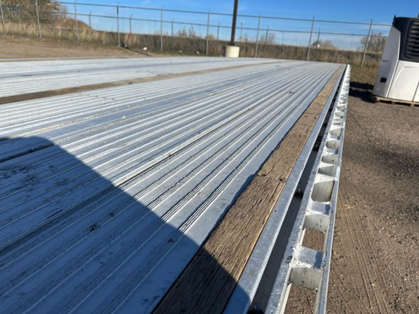 Aluminum drop deck trailer bed of a 2018 Reitnouer Maxmiser showing corrugated metal surface with wood edge trim and raised side channels.