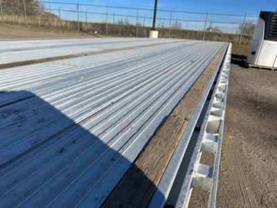 Aluminum drop deck trailer bed of a 2018 Reitnouer Maxmiser showing corrugated metal surface with wood edge trim and raised side channels.
