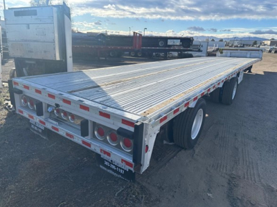 Aluminum drop deck trailer showing rear and side with dual axles and taillights.