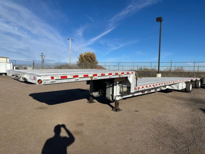 Trailer chassis showing low-profile aluminum drop deck with front landing gear and extended deck sections, Reitnouer Maxmiser branding not visible, flatbed with reflective tape along rails.