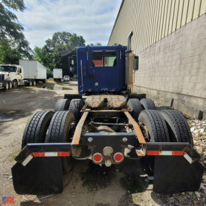 Rear view of a blue Freightliner Columbia 120 tractor chassis showing fifth wheel, dual rear axles, and dual tires.