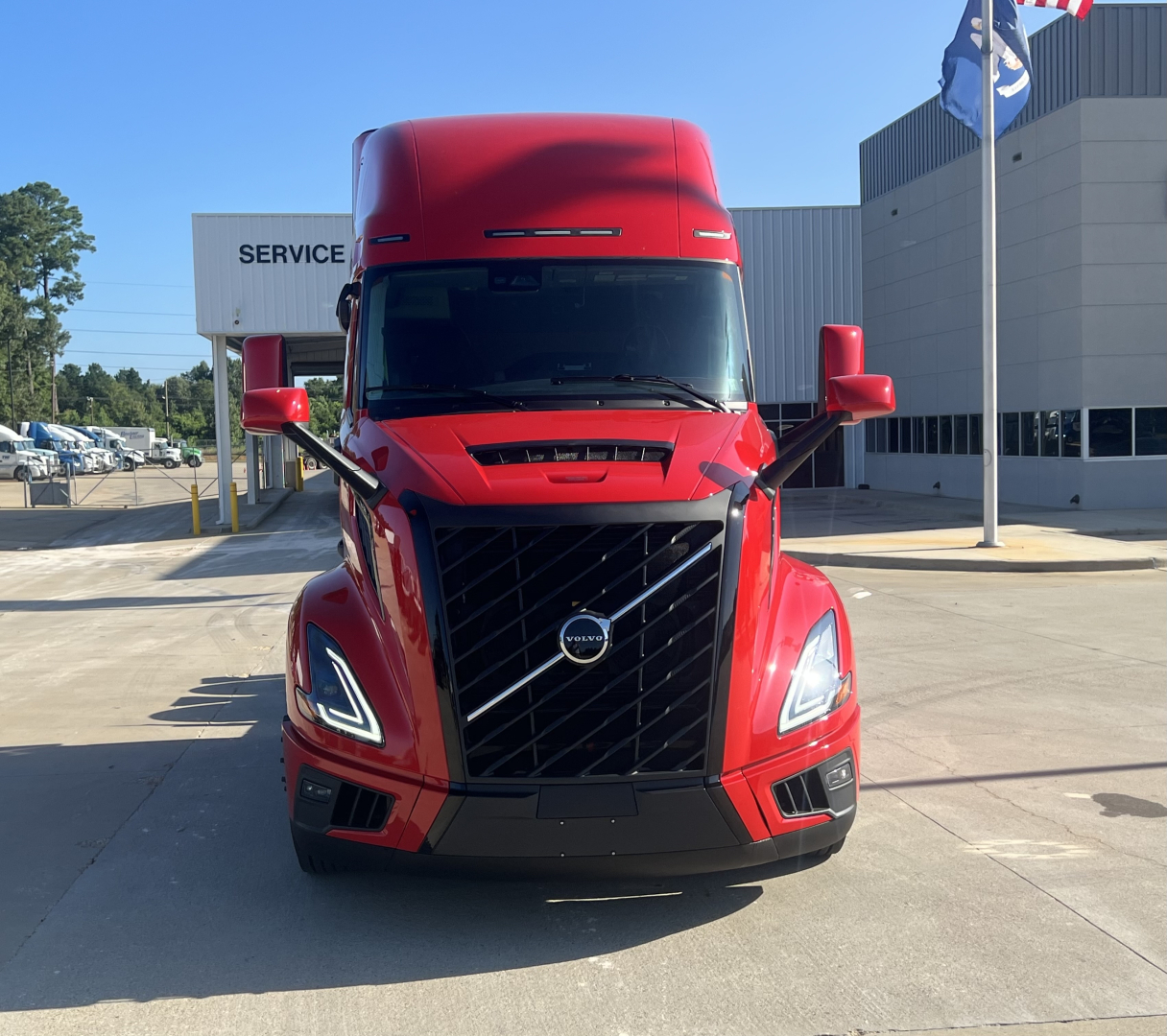 Volvo VNL64T660 tractor front view showing bold grille, daytime running lights, red paint, and large windshield.