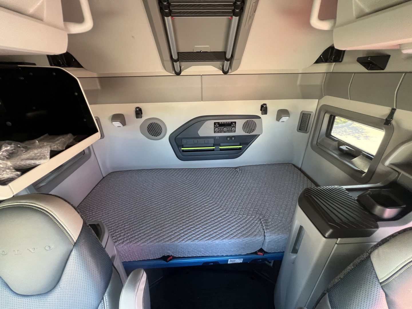 Volvo VNL64T660 sleeper cab interior showing bed area with storage lockers and overhead compartments.
