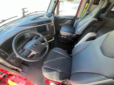 Volvo VNL64T660 cab interior showing steering wheel, dashboard, driver seat and passenger seat with grey fabric, center console, and floor mats