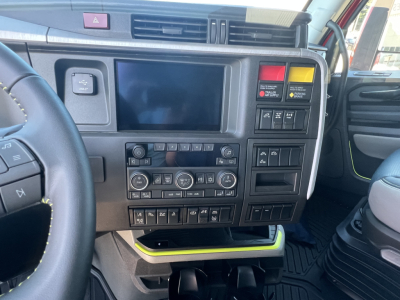 Dashboard cockpit of a Volvo truck showing central touchscreen, climate controls, switches, and USB/communication panels.