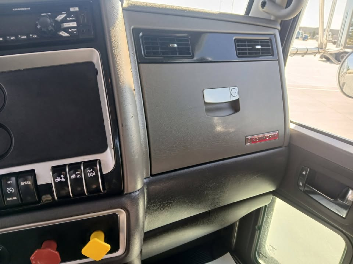 Kenworth T800 dash area with glove box and center console, interior view from passenger side showing dash controls.