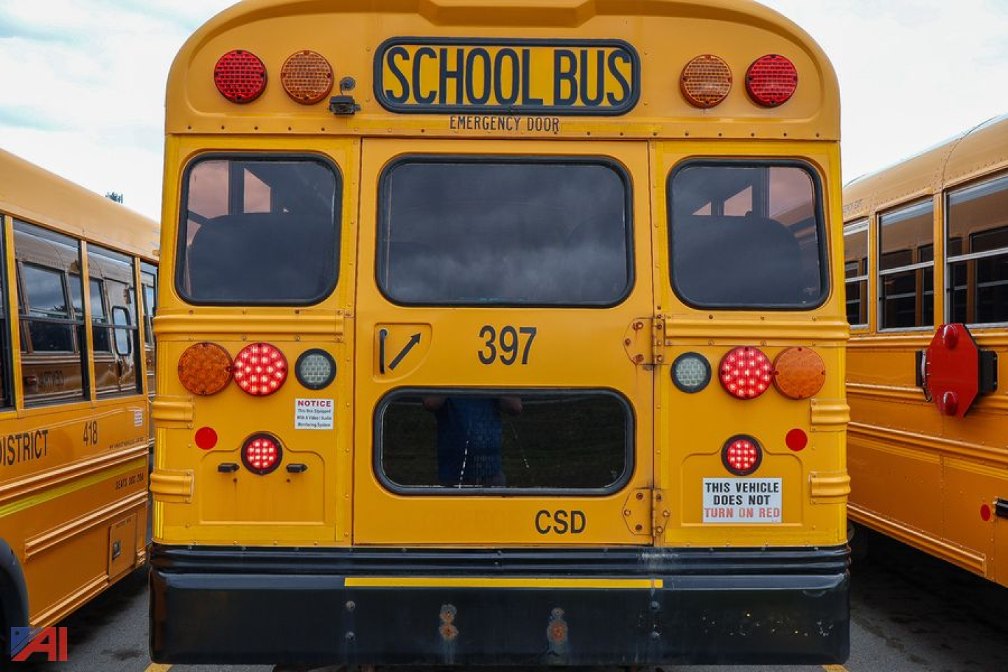 School bus rear view showing Emergency Door, 'SCHOOL BUS' sign, 397 number, and various lights.